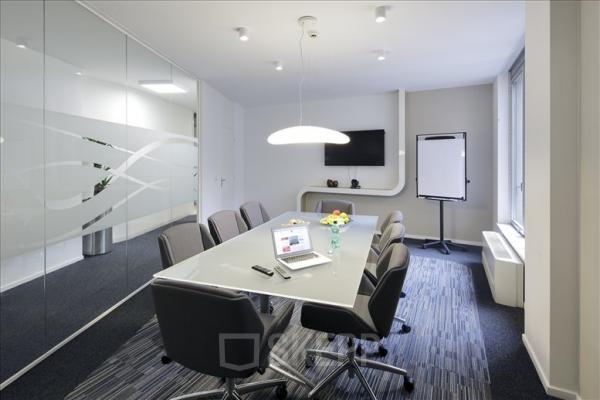 Modern office space with a glass wall, meeting table, chairs, TV, and flipchart in Avenue Louise, Brussels. Perfect for office space rental.