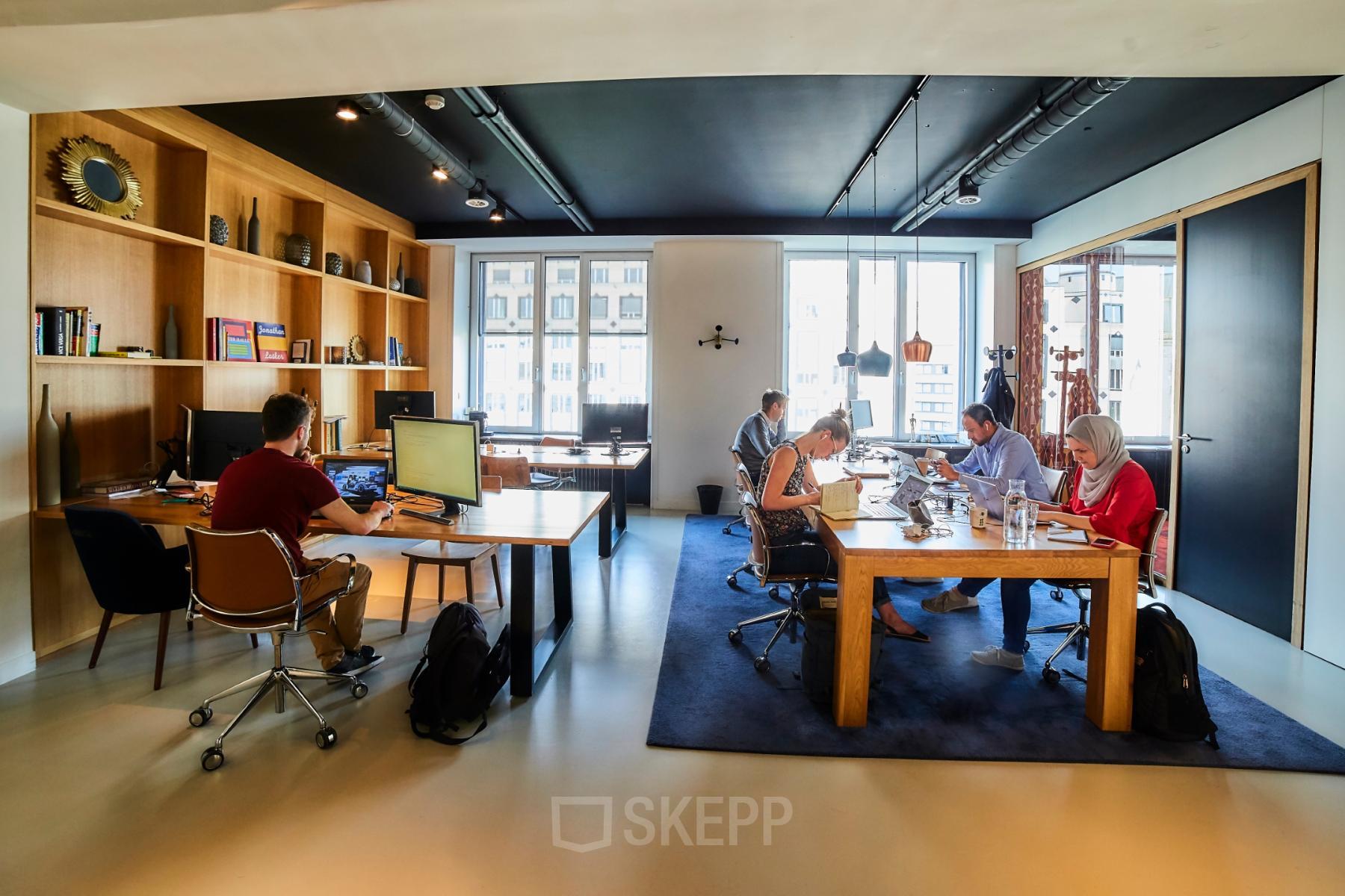Workspaces in office for rent at Louizalaan / Avenue Louise 54, Brussels Elsene, featuring modern furnishings, large windows, and office workers collaborating around desks.
