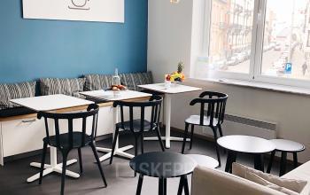 Interior of office lounge area at Avenue Louise 367, Brussels Elsene, with modern furniture, black tables and chairs, blue wall accent, and large window with street view.