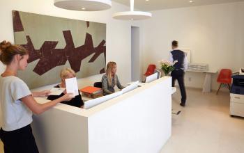 Modern reception area at Louizalaan / Avenue Louise 367 in Brussels Elsene, featuring a front desk with employees working and assisting visitors; an ideal office space rental option.