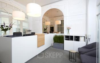 Receptie van het kantoor te huur op Priester Cuypersstraat / Rue Abbé Cuypers 3 in Brussel Etterbeek, Brussel, met een moderne balie, bloemen en stoelen.