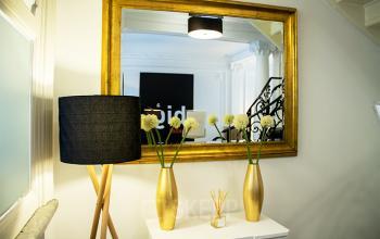 Kantoorruimte te huur aan Priester Cuypersstraat / Rue Abbé Cuypers 3 in Brussel Etterbeek, met smaakvolle decoratie, spiegel en bloemen op een kastje.