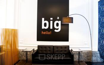 Kantoorruimte te huur op Priester Cuypersstraat / Rue Abbé Cuypers 3, Brussel Etterbeek. Moderne zithoek met zwarte bank en grote wanddecoratie.