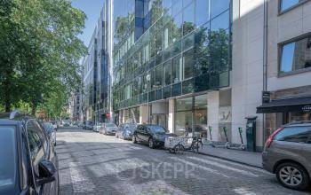 Exterior view of office building at Meeûssquare / Square de Meeûs 37 in Brussels European District with glass façade and parked cars.