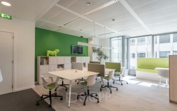 Bright office space rental at Meeûssquare 37, Brussels European District, featuring modern workstations, green accent walls, and ample natural light.