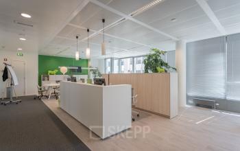 Modern office space at Meeûssquare / Square de Meeûs 37 in Brussels European District, featuring a reception area with a sleek desk, plants, and modern light fixtures.