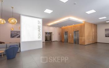 Modern office building interior at Meeûssquare / Square de Meeûs 37 in Brussels European District, showcasing elevators and a stylish waiting area, ideal for office space rental.