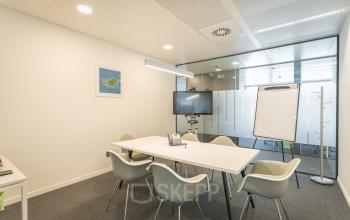 Modern conference room with a white table, gray chairs, a TV, and a flip chart at Meeûssquare / Square de Meeûs 37 in Brussels European District, ideal for office space rental.