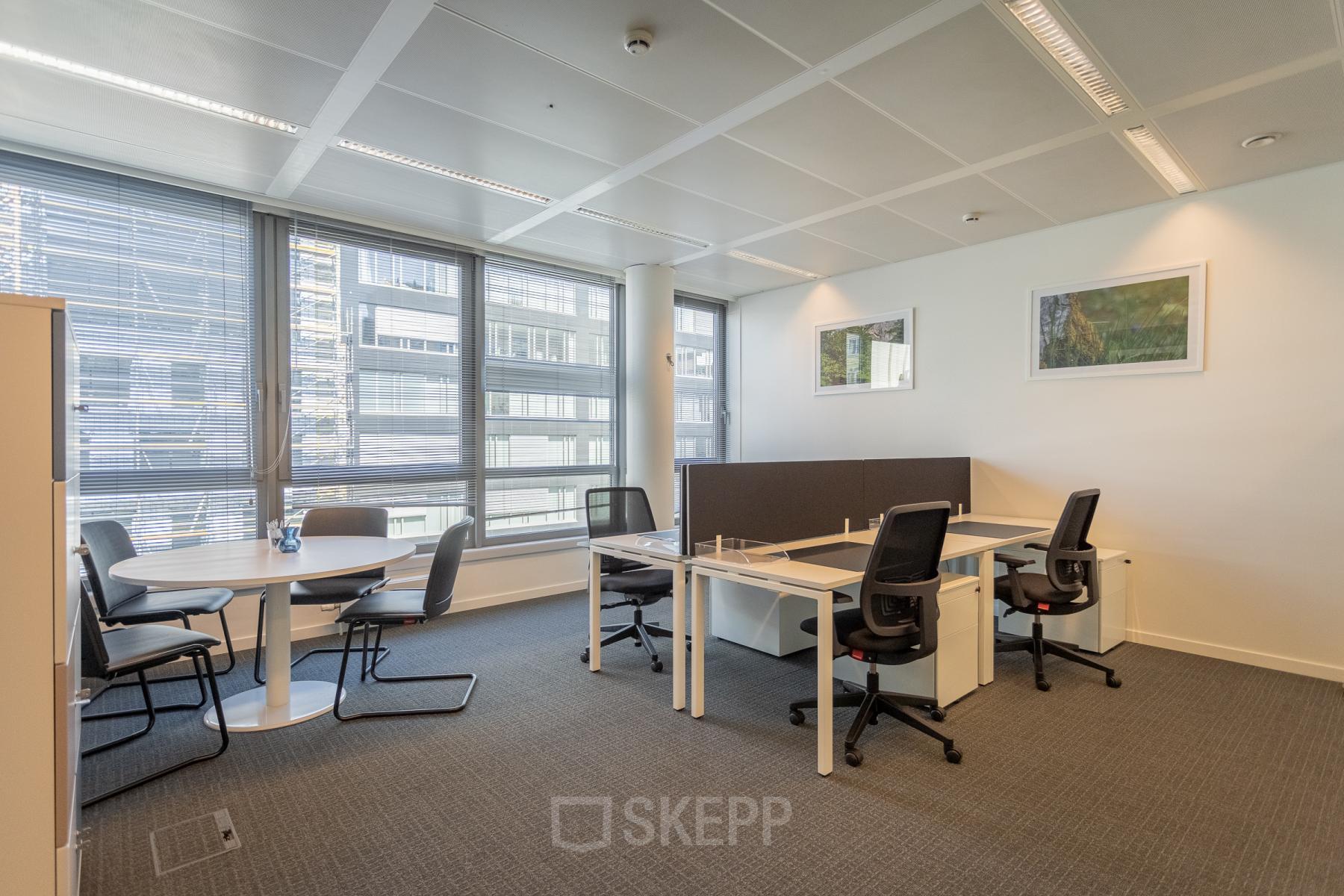 Modern office space rental with large windows, workstations, and a small round meeting table, located at Meeûssquare / Square de Meeûs 37 in Brussels European District.