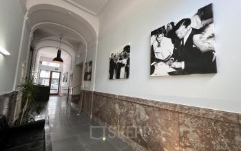 Ingang van een kantoorpand op Rue d’Arlon 25, Brussel Europese Wijk, met kunstwerken aan de muur en een zwarte sofa.