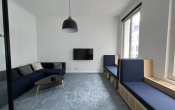 Kantoorruimte te huur op Rue d'Arlon 25, Brussel Europese Wijk, met moderne inrichting, donkere banken, een salontafel en een wandtelevisie.