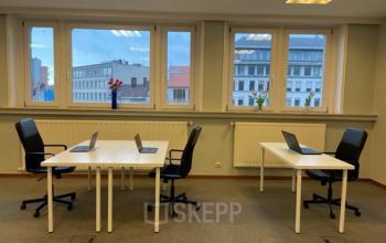 Kantoorruimte te huur op Avenue Palmerston 3, Brussel, Europese Wijk. Moderne ruimte met vier werkstations, bureaustoelen en laptops, grote ramen met uitzicht op gebouwen.