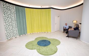 Kantoorruimte te huur op Avenue Palmerston 3 in Brussel Europese Wijk met kleurrijke gordijnen en bloemenvormig vloerkleed. Twee personen hebben een zakelijk gesprek in een comfortabele lounge setting.