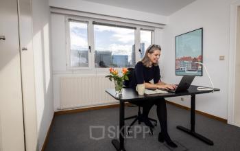 Kantoorruimte te huur op Avenue Palmerston 3, Brussel Europese Wijk, ingericht met een bureau, stoel en bloemenvaas, met zicht op de stad.