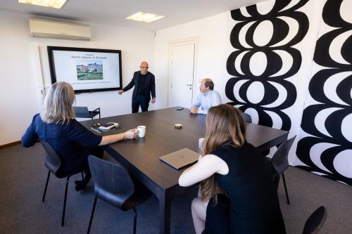 Office space rental at Avenue Palmerston 3, Brussels European District featuring a meeting with professionals around a large table and a presentation screen in a modern conference room.