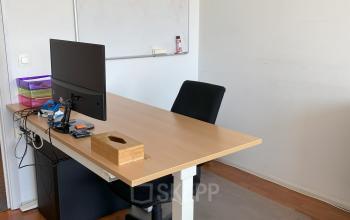 Kantoorruimte te huur in Brussel Europese Wijk, Avenue des Arts 3-5. Interieur met houten bureau, stoel en computer. Eenvoudig ingericht met houten vloer en een whiteboard aan de muur.
