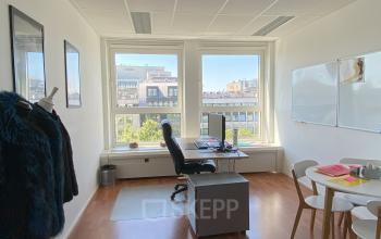 Kantoorruimte te huur in Brussel Europese Wijk, Avenue des Arts 3-5, met houten vloer, grote ramen, bureau en stoelen, geschikt voor zakelijke activiteiten.