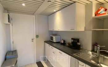 Moderne kitchenette in kantoorruimte te huur, met witte kasten en strakke tegelvloer, gelegen in Avenue des Arts 3-5, Europese Wijk, Brussel.