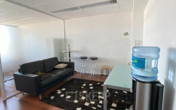 Modern ingerichte kantoorruimte te huur op Avenue des Arts 3-5 in de Europese Wijk, Brussel, met stijlvol meubilair zoals een zwarte bank, glazen tafel, en waterkoeler, wat een productieve werksfeer biedt.