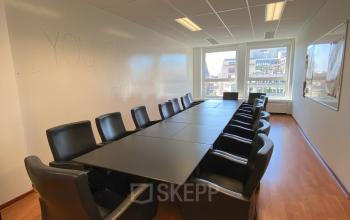 Vergaderzaal op Avenue des Arts 3-5 in Brussel Europese Wijk, met lange tafel en leren stoelen, perfect voor zakelijke bijeenkomsten. Ideaal als kantoorruimte te huur.