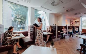 Modern office space in Brussels European District at Robert Schumanplein 2-4 with people working in comfortable booths, ideal for office space rental.