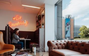 Cozy office space with a person working on a laptop, featuring comfortable seating and decorative elements in the Brussels European District, perfect for office space rental.