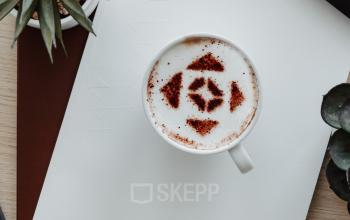 A stylish office desk with a keyboard, coffee cup, notebook, pen, and plants, ideal for office space rental.