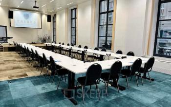 Ruime kantoorruimte te huur in de Europese Wijk van Brussel, gelegen op Rue des Colonies 56, met grote vergadertafels en comfortabele stoelen, ideaal voor zakelijke bijeenkomsten.