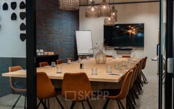 Stijlvolle vergaderruimte met lange tafel, omringd door leren stoelen en verlichte hanglampen. Ideaal kantoorruimte te huur in de Europese Wijk voor professionele bijeenkomsten.