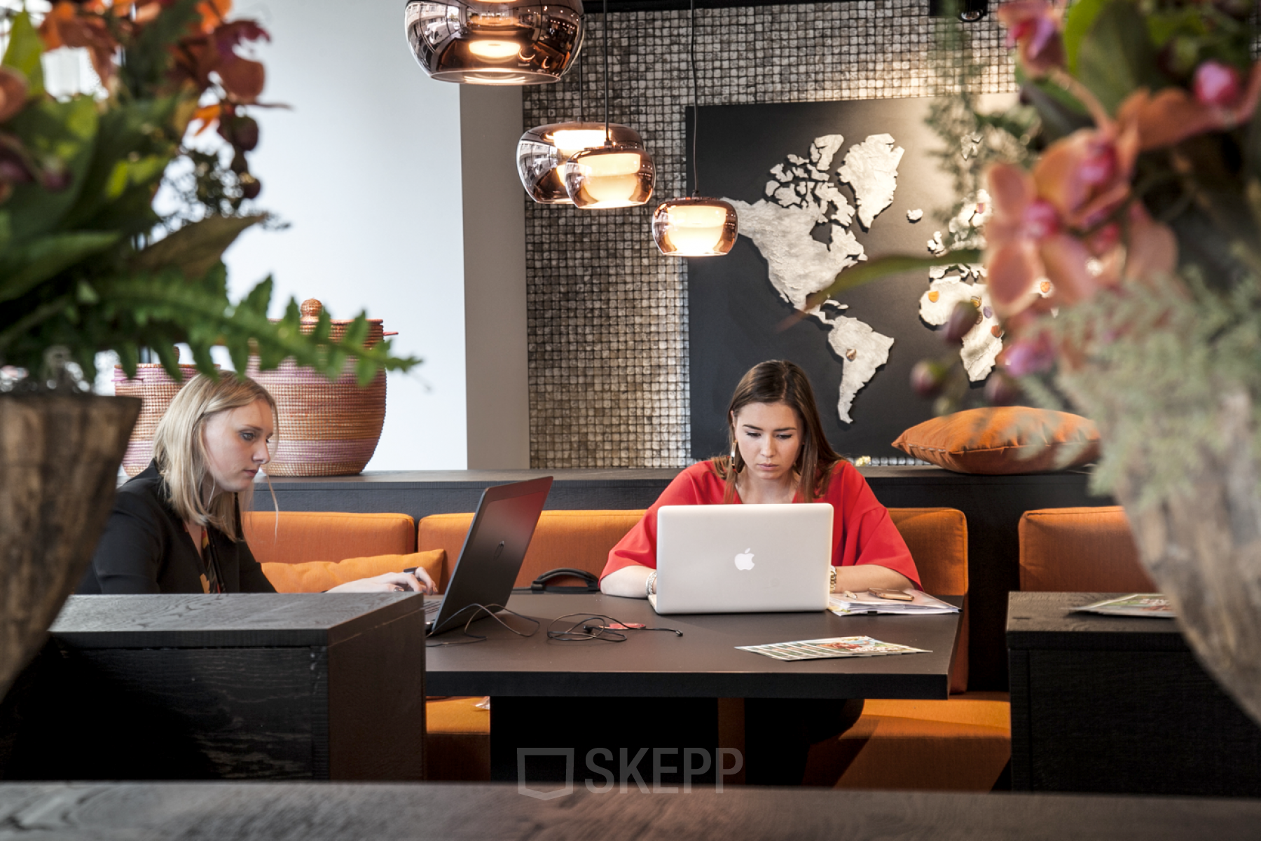 Vibrant office space with modern decor at Marnixlaan / Avenue Marnix 13-17, in Brussels European District. Two people working on laptops in a cozy lounge area.