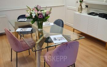 Moderne kantoorruimte te huur op Breydelstraat / Rue Breydel 34-36 in Brussel Europese Wijk, voorzien van stijlvolle meubels, een glazen tafel en pastelkleurige stoelen.