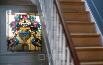 Binnenkant van kantoor te huur op Breydelstraat / Rue Breydel 34-36 in Brussel Europese Wijk, met glazen raamdecoratie en houten trap.
