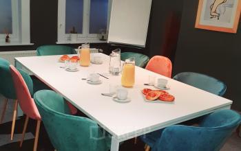 Vergaderruimte in Brussel Europese Wijk met kleurrijke stoelen rond een witte tafel, voorzien van koffie en sinaasappelsap.