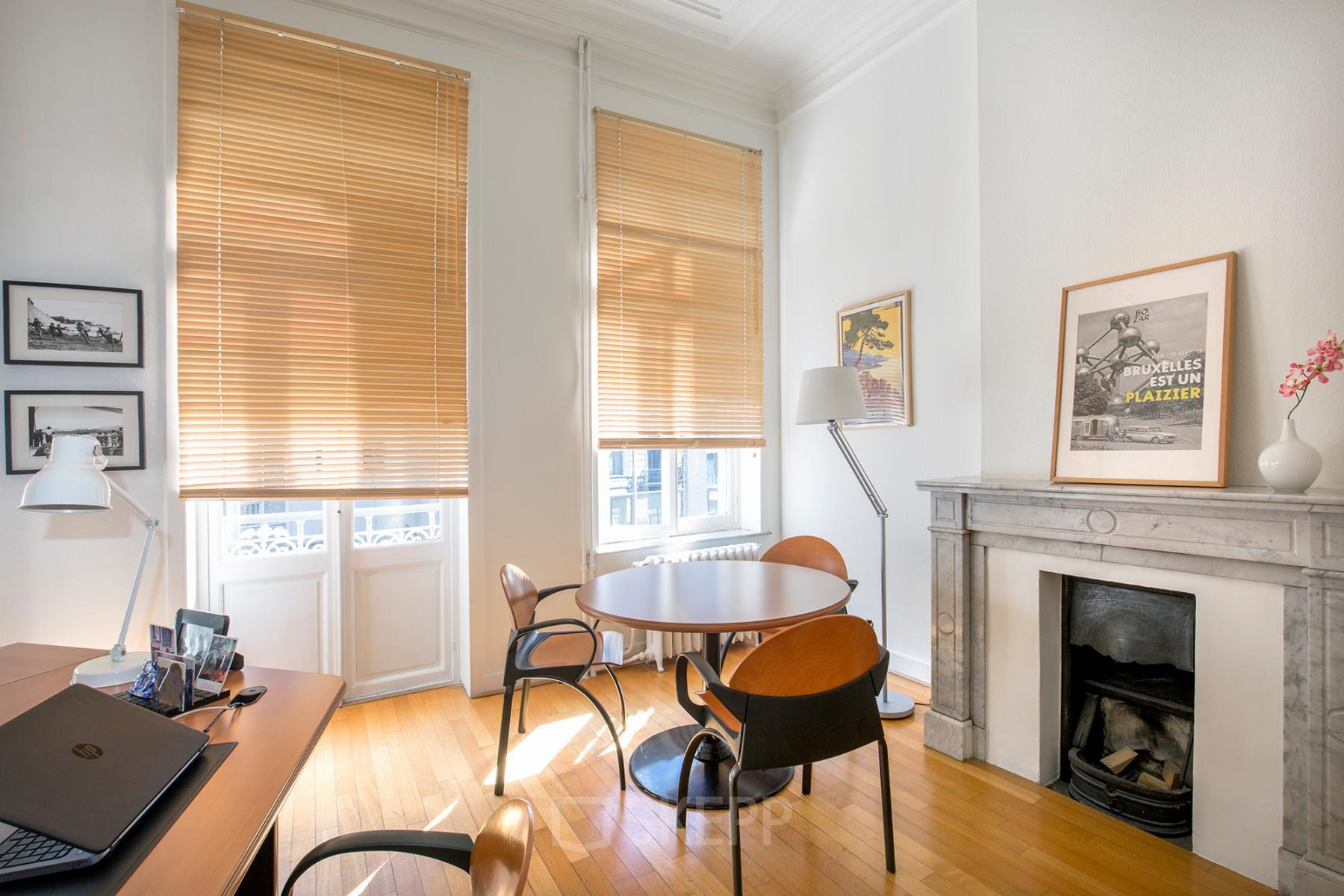 Cozy office space with a round meeting table, chairs, desk, and fireplace, located at Breydelstraat / Rue Breydel 34-36 in Brussels European District.