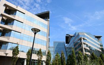 Modern kantoorgebouw aan Woluwedal 18-22 in Brussel Sint-Stevens-Woluwe met grote ramen en omgevende vegetatie, kantoorruimte te huur beschikbaar.