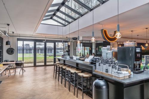 Interior view of office space rental at Rietbaan 2-12, Capelle aan den IJssel, featuring a well-lit lounge area with bar seating, modern lighting, and large windows overlooking greenery.