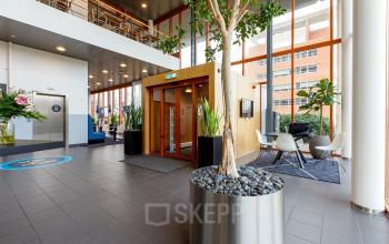 Modern office entrance at Fascinatio Boulevard 562, Capelle aan den IJssel, featuring sleek decor with seating area and plants, ideal for office space rental.