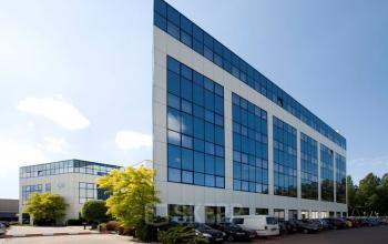 Modern office building at Rietbaan 40-42, Capelle aan den IJssel, featuring sleek glass facade and spacious parking area. Ideal location for office space rental.