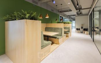 Modern office space with wood and green accents at Rietbaan 40-42 in Capelle aan den IJssel, featuring stylish seating booths and ceiling lighting, ideal for meetings or collaborative work.