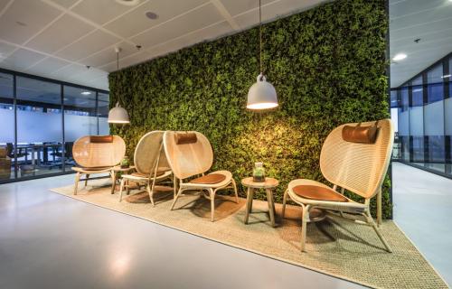 Modern office lounge at Rietbaan 40-42, Capelle aan den IJssel, featuring rattan chairs and green wall, offering a refreshing setting for work breaks. Ideal for businesses seeking unique office space rental.