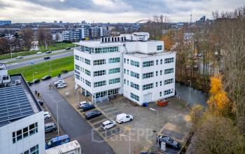 Exterior view of a modern white office building located at Rhijnspoor 209-263 in Capelle aan den IJssel, featuring ample parking space, perfect for businesses looking to rent office space.