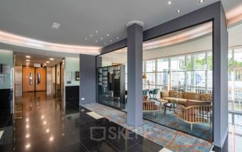 Modern interior of office space at Rhijnspoor 209-263, Capelle aan den IJssel, showcasing a stylish seating area with glass walls and sleek flooring. Ideal for office space rental.