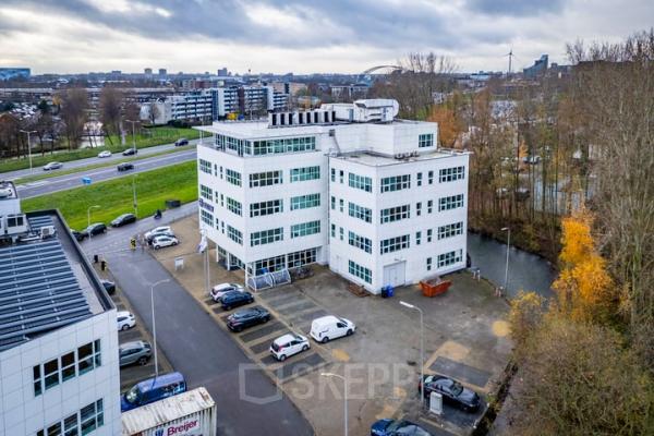 Exterior view of a modern white office building located at Rhijnspoor 209-263 in Capelle aan den IJssel, featuring ample parking space, perfect for businesses looking to rent office space.