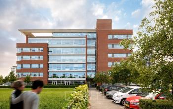 Exterior view of a modern office building at Fascinatio Boulevard 522, Capelle aan den IJssel, featuring a brick facade and large windows, surrounded by greenery and parked cars, ideal for office space rental.