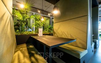 Contemporary workspaces at Fascinatio Boulevard 522, Capelle aan den IJssel featuring cozy booth seating with greenery and modern lighting, ideal for collaborative office space rental.