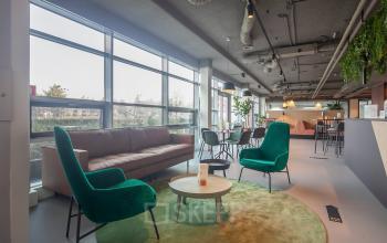 Modern and bright lounge area with plush green chairs and a comfortable sofa, ideal for relaxing or informal meetings at Fascinatio Boulevard 522. Explore office space rental options here in Capelle aan den IJssel.