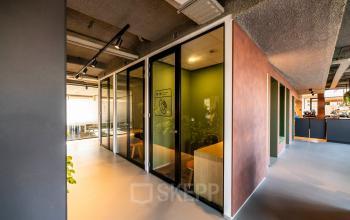 Modern office interior at Fascinatio Boulevard 522, Capelle aan den IJssel, featuring glass-enclosed meeting rooms and a sleek, open design ideal for office space rental needs.