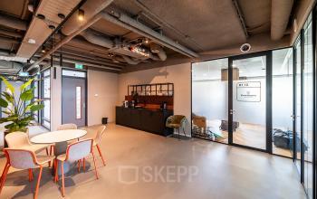 A modern office interior at Fascinatio Boulevard 522, Capelle aan den IJssel, featuring a collaborative workspace with a round table and chairs, adjacent to a coffee area for relaxed meetings or breaks.