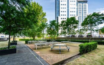 Outdoor seating area at Rivium Quadrant 75, Capelle aan den IJssel, surrounded by trees, providing an ideal setting for informal meetings; perfect for businesses seeking office space rental.