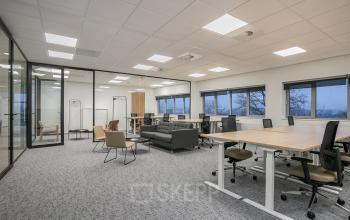 Spacious, furnished office space with modern workstations and a comfortable lounge area at Rivium Quadrant 75, Capelle aan den IJssel. Ideal for office space rental with ample natural light and sleek design.